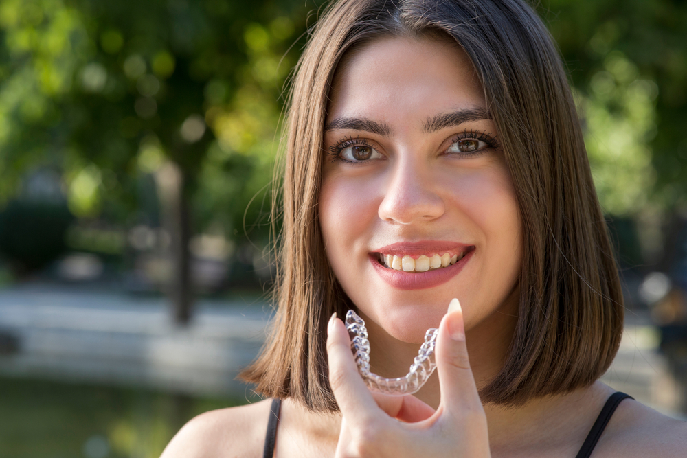 woman-smiling-holding-Invisalign-retainer