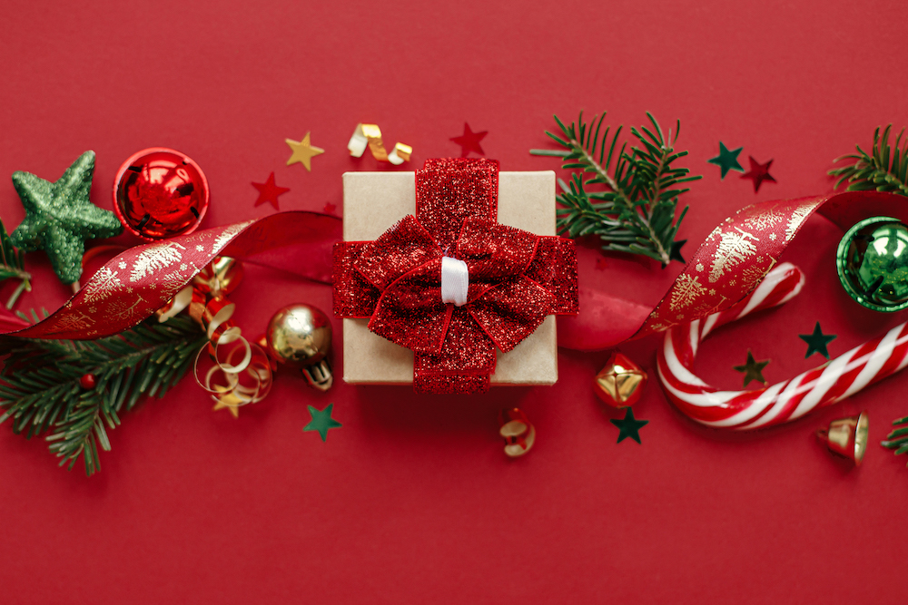 A Christmas present on a red background and surrounded by other holiday decorations